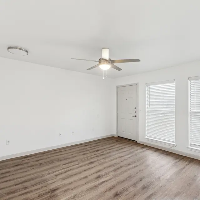 A room with a ceiling fan and wooden flooring.